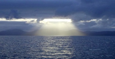 Almost biblical scene sun casting rays through clouds to Sound of Jura